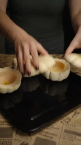 Hands preparing a small white pumpkin by cutting off the top for a soup bowl