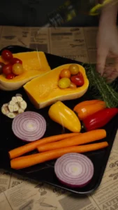 Halved butternut squash with bell peppers, carrots, tomatoes and onion arranged for roasting