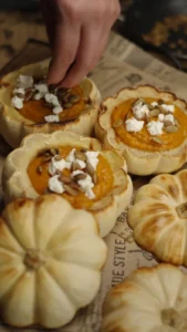 Roasted white mini pumpkins filled with orange squash soup and topped with cheese and seeds