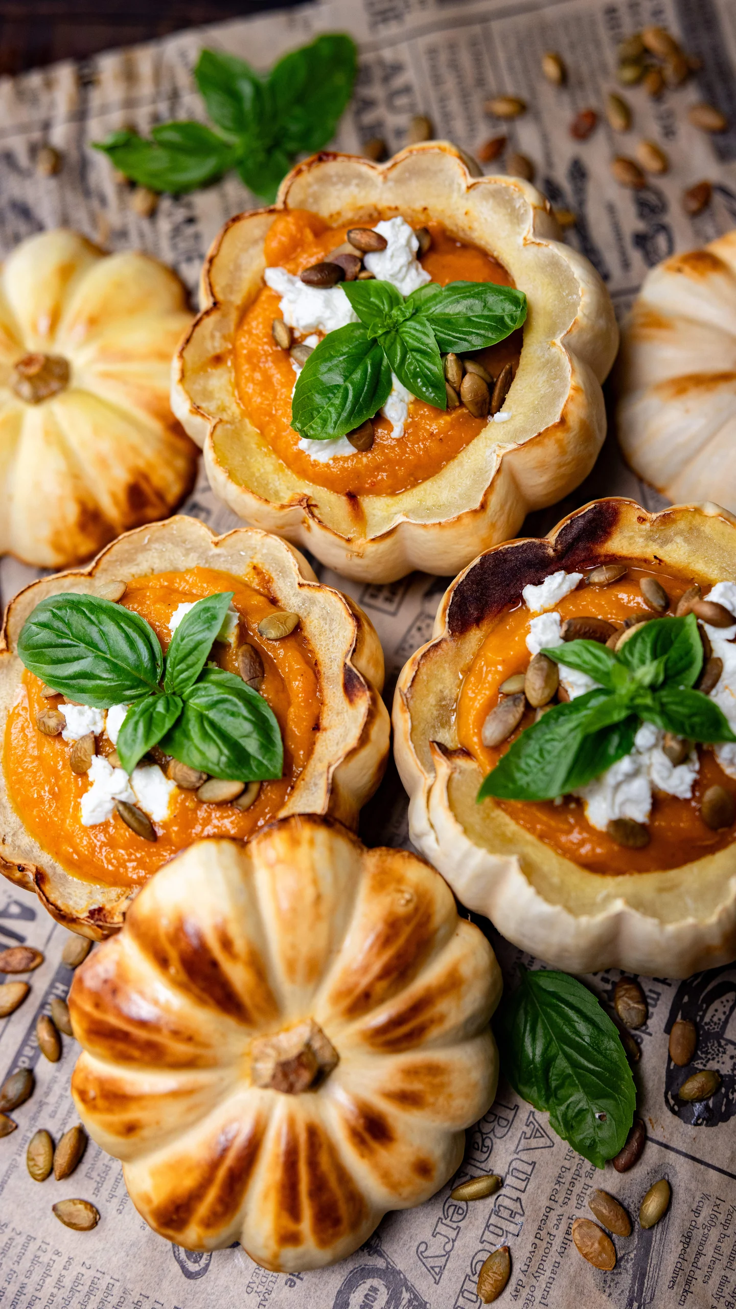 White pumpkin bowls filled with golden butternut squash soup and basil